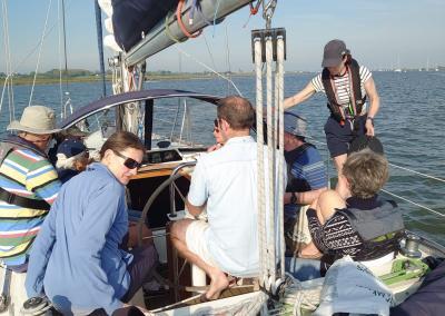 Taken from the stern of a Moody sailing boat, looking forward at the cockpit where there are 5 people sitting. The boat is slightly heeled to port.